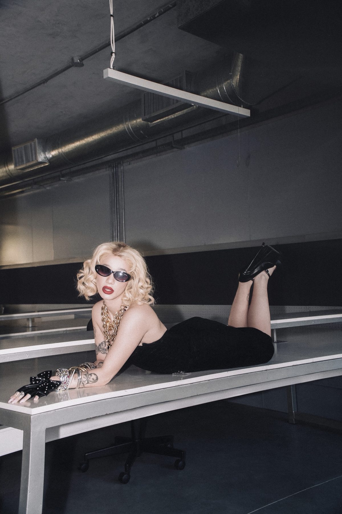 Ángela Torres lying on a desk under industrial ducts
