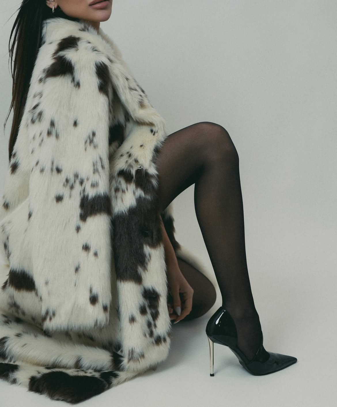 Spotted fur coat and black patent stiletto in a cropped studio frame