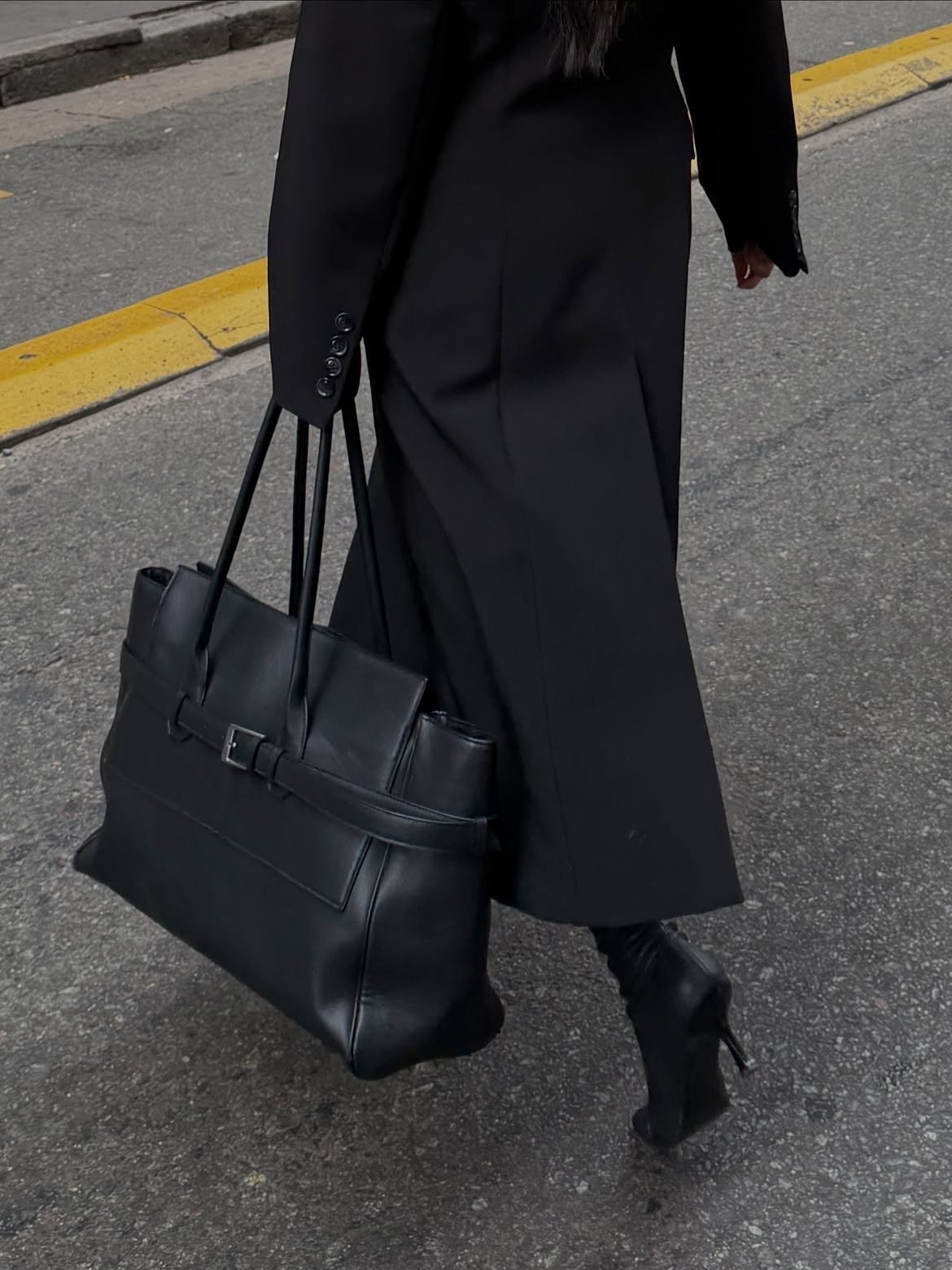 Black tailoring and a leather tote crossing the street