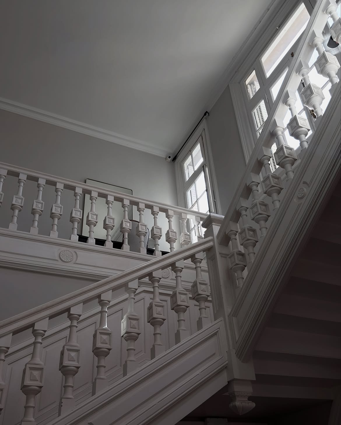 White staircase with turned balusters in soft window light