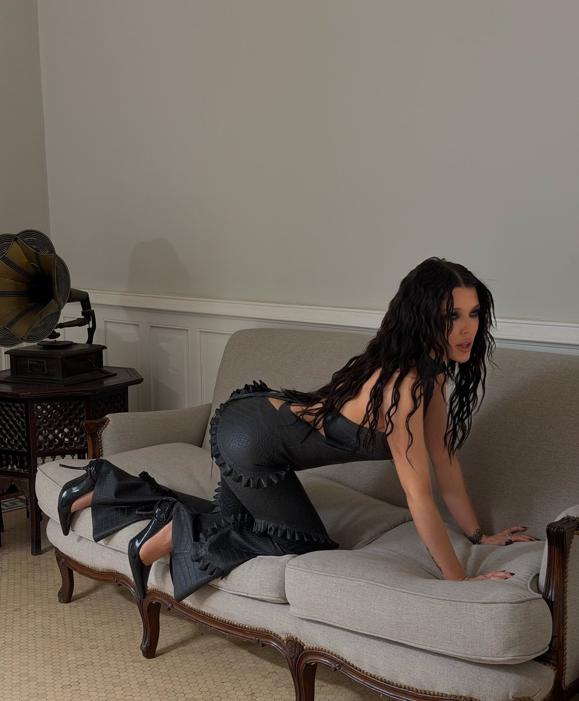 On all fours across a linen sofa, ruffled croc-leather flares and patent heels
