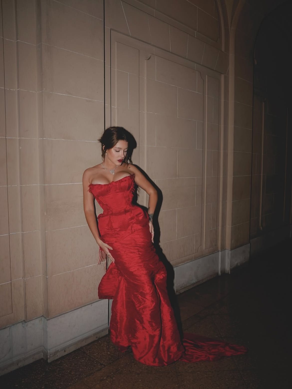 Sofía Gonet leaning against a stone wall at night, red train on the floor