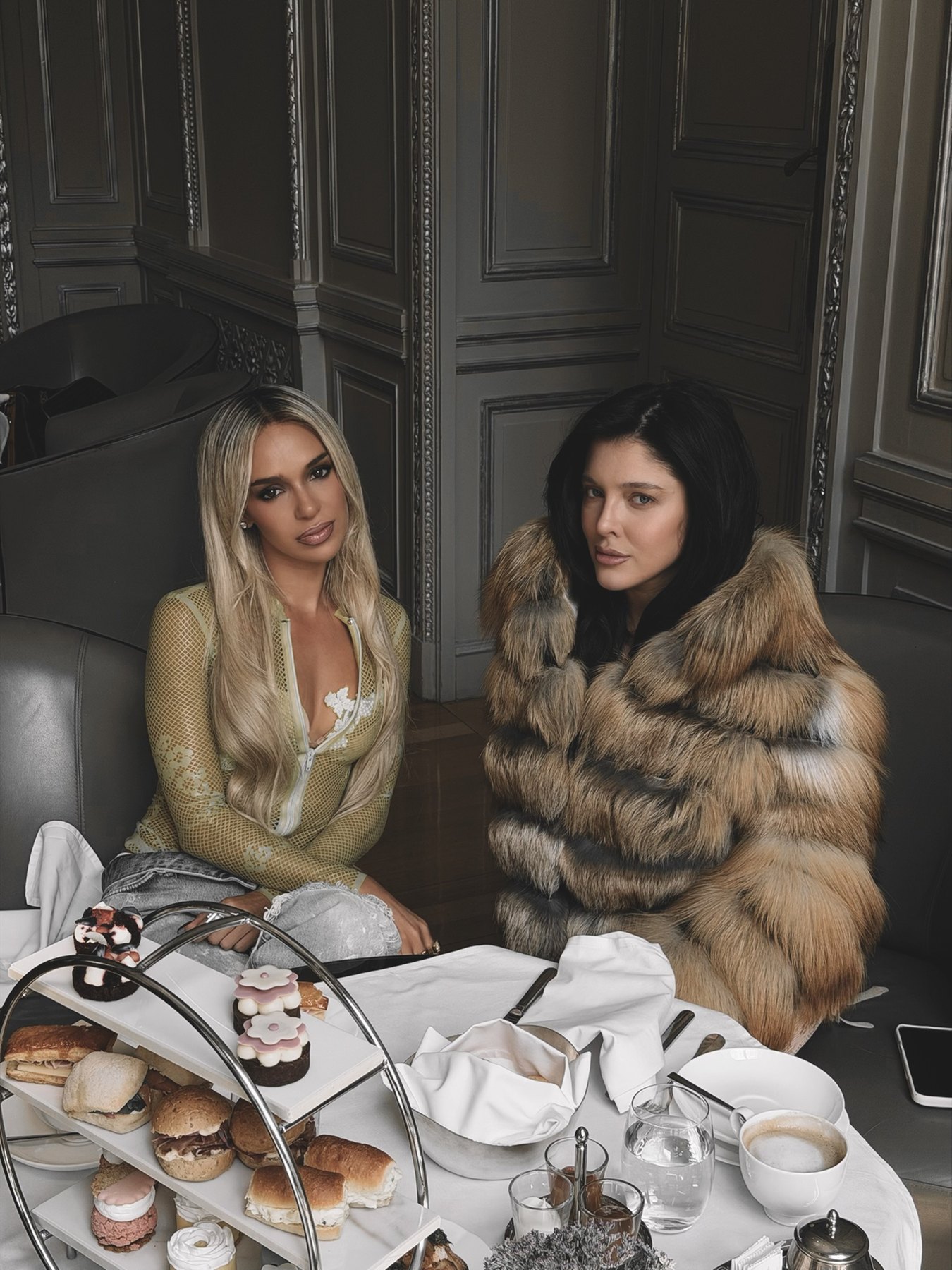 Bad Gyal and Sofía Gonet seated at a tea table with pastries