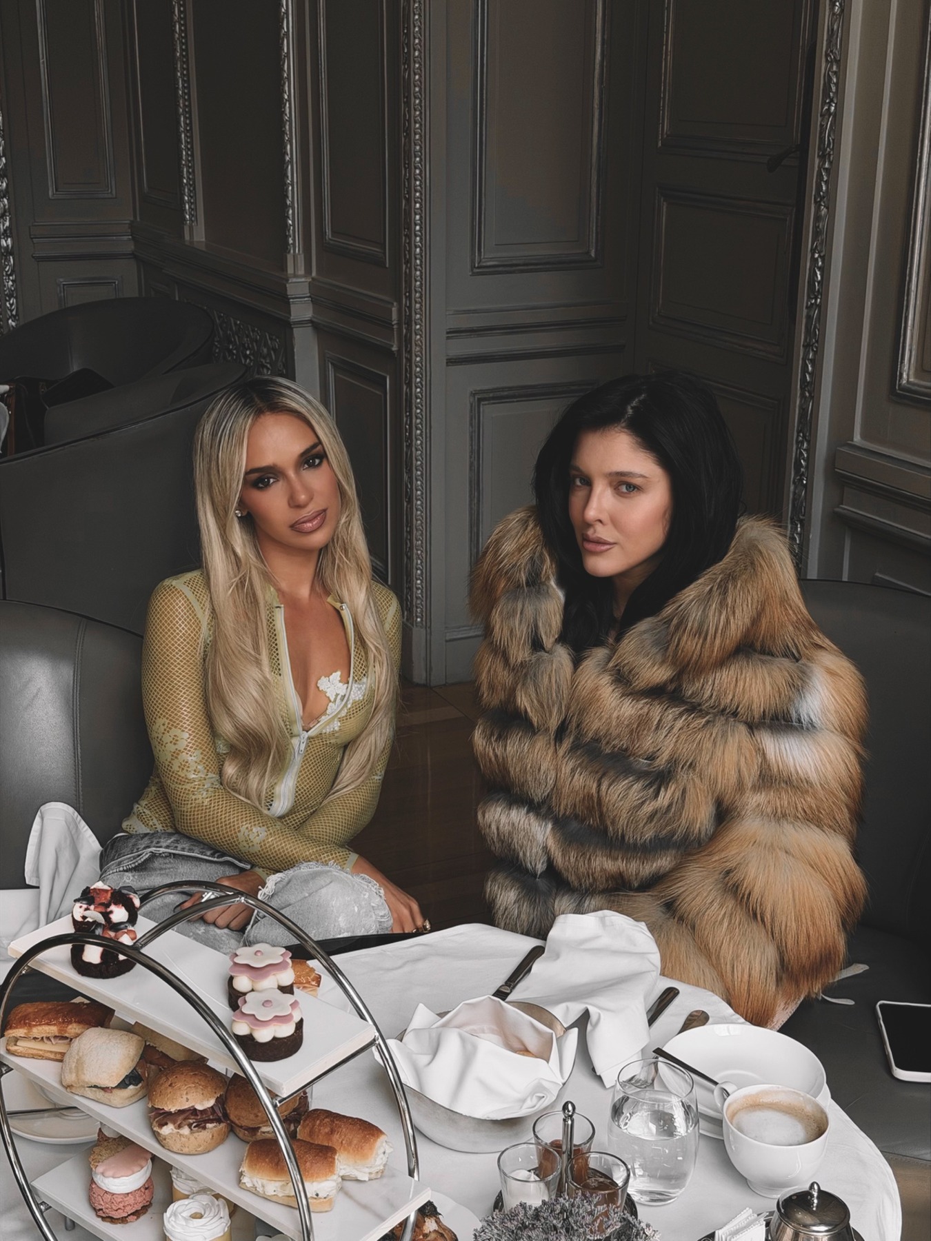Bad Gyal and Sofía Gonet seated at a tea table with pastries