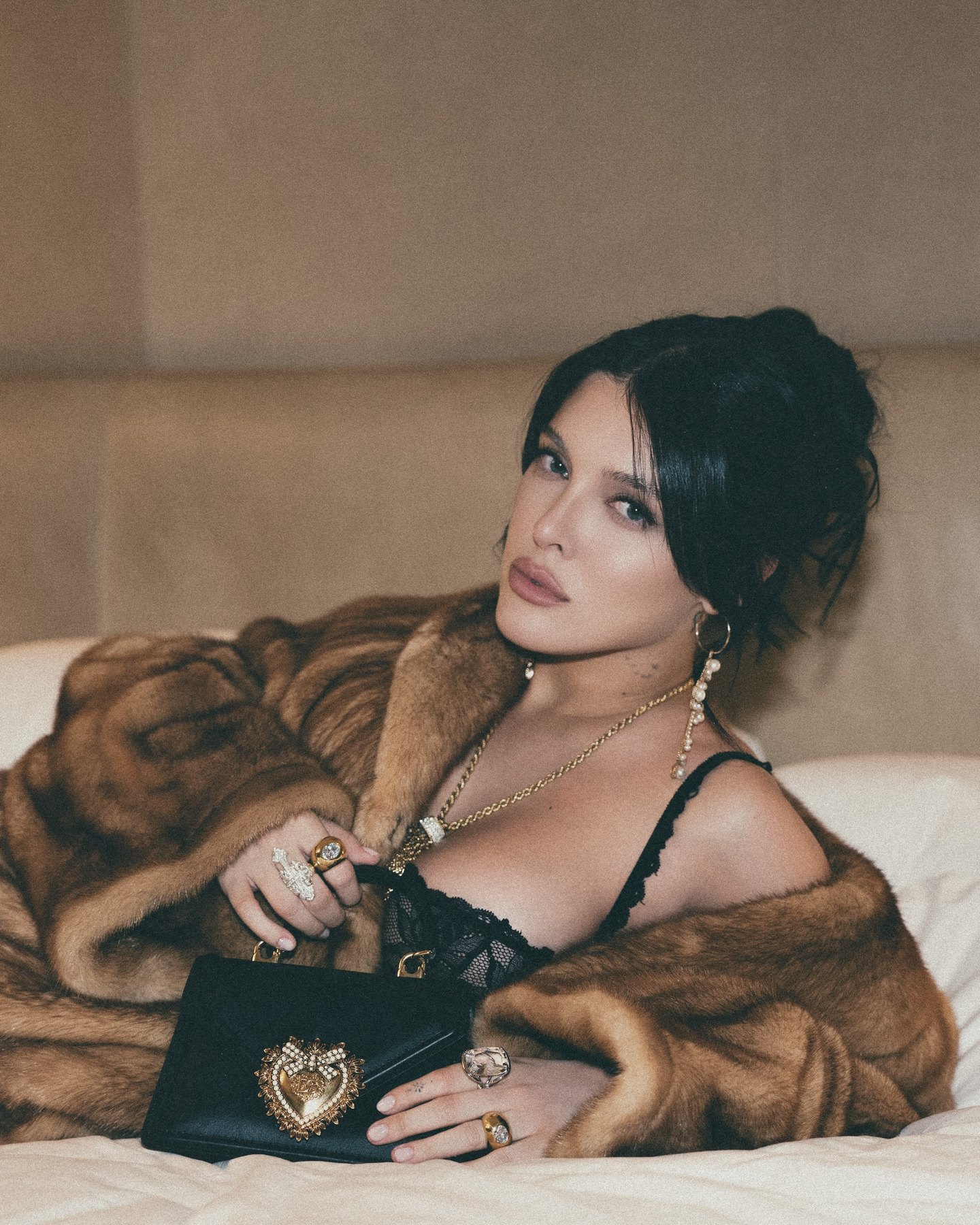 Sofía Gonet in a mink coat and black lace with a Dolce & Gabbana Devotion bag on white sheets