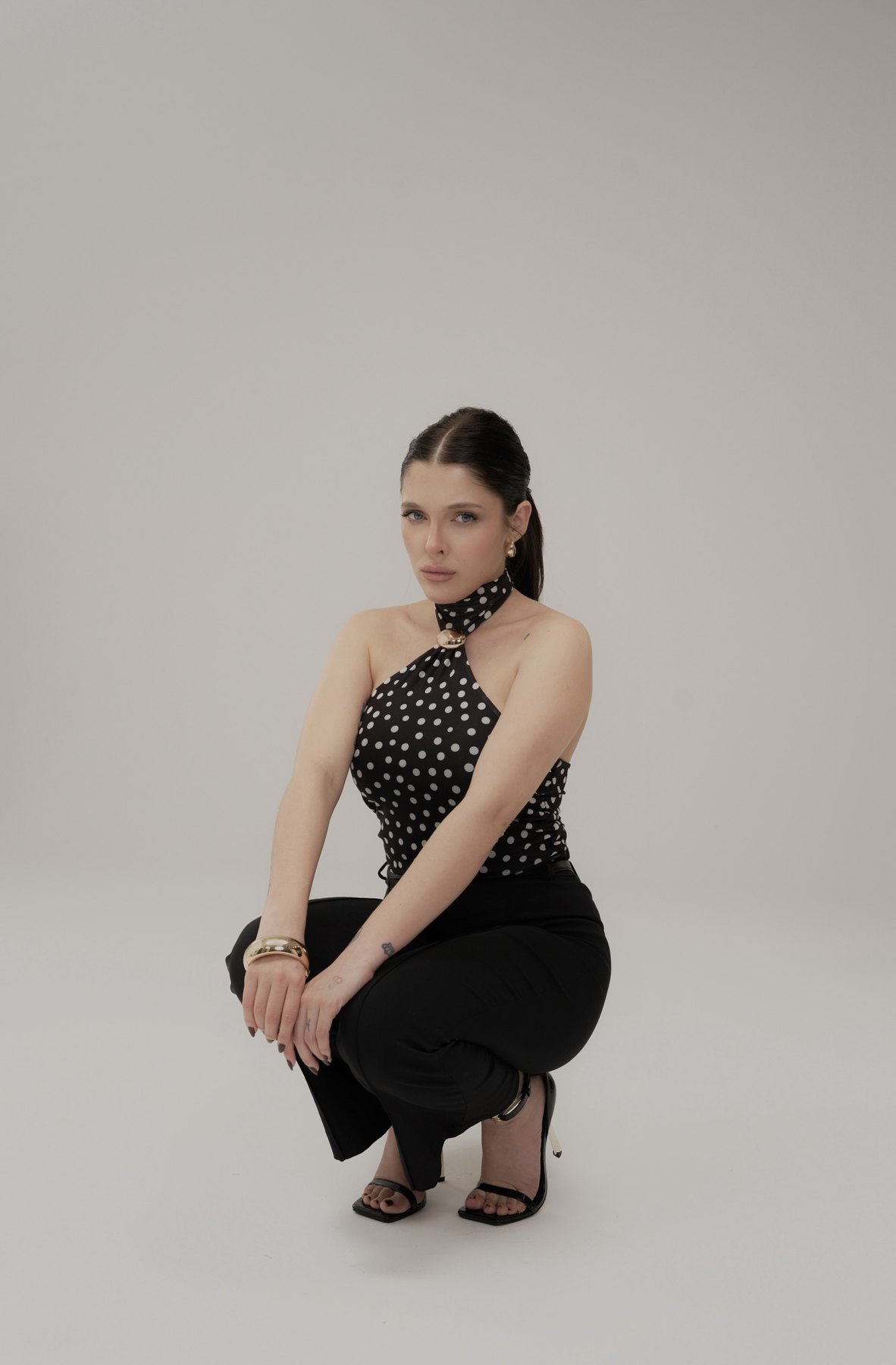 Sofía Gonet crouching in the polka-dot halter and black trousers