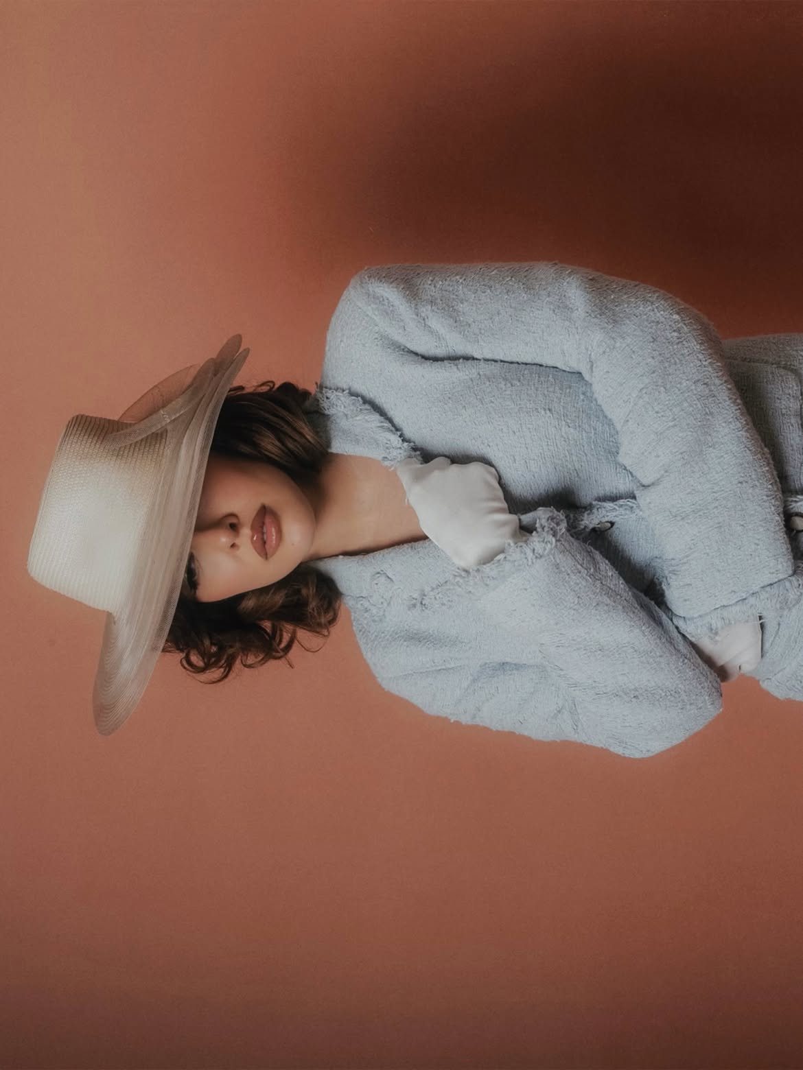 Sofía Gonet under a wide hat, turned on its side against terracotta
