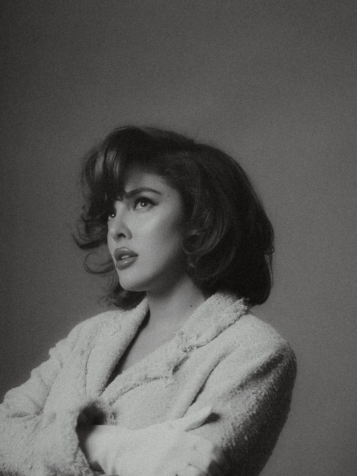 Black and white portrait of Sofía Gonet in a textured coat, looking up